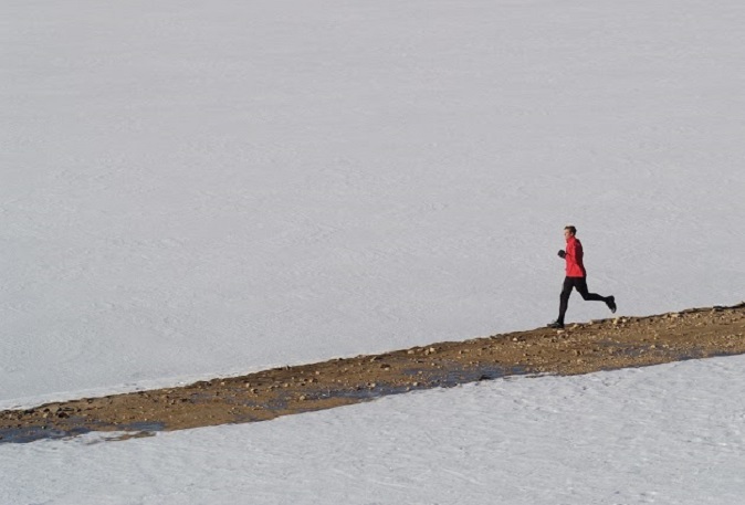 Man Running On Trail Against Snow Covered Mountains